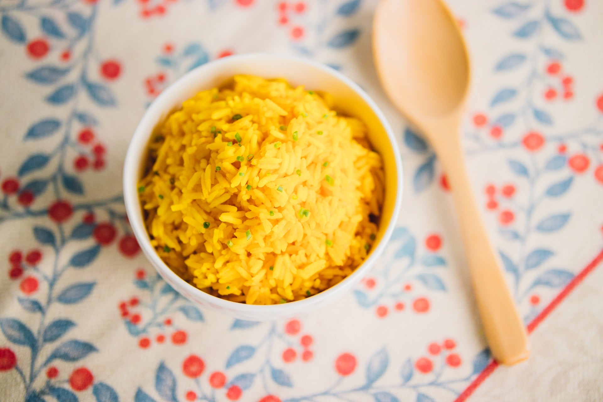 Turmeric Rice in a bowl with a wooden spoon at the side